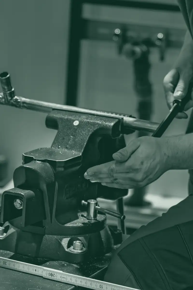 A plumber's hands bending copper pipe in a workshop