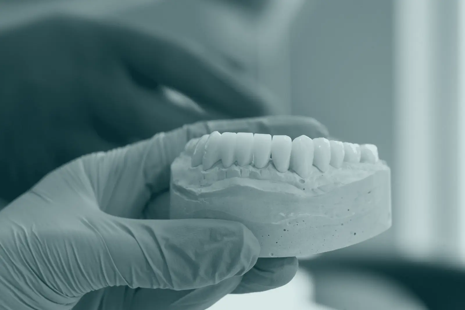 Gloved hands holding a dental model in a lab